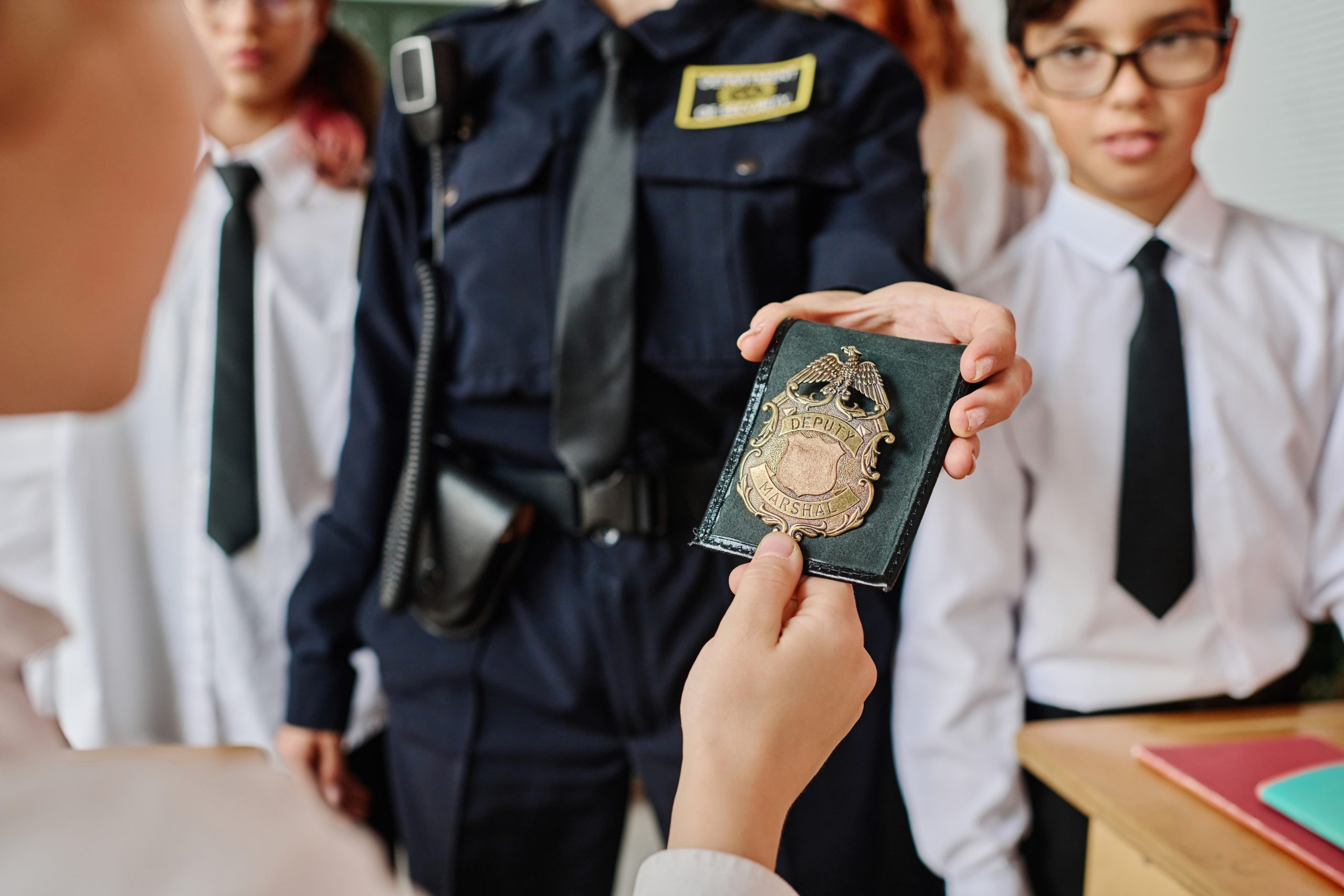 Unrecognizable female office showing her police badge to kids during career guidance class at school